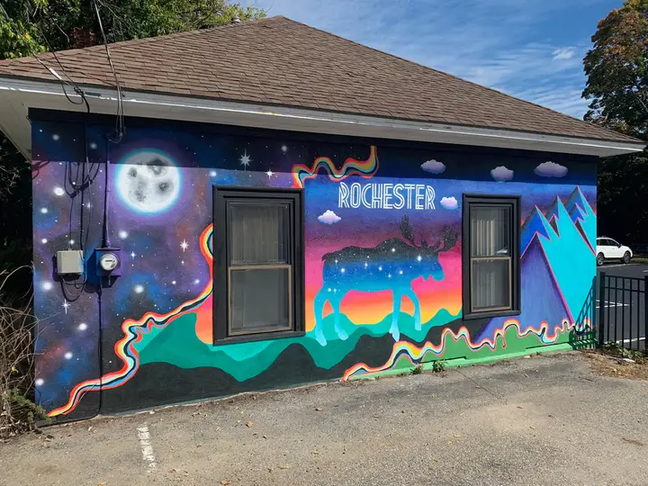 The Rochester moose mural - a moose filled with a starry night sky against northern lights, a full moon, and mountains - painted on a downtown Rochester, New Hampshire building